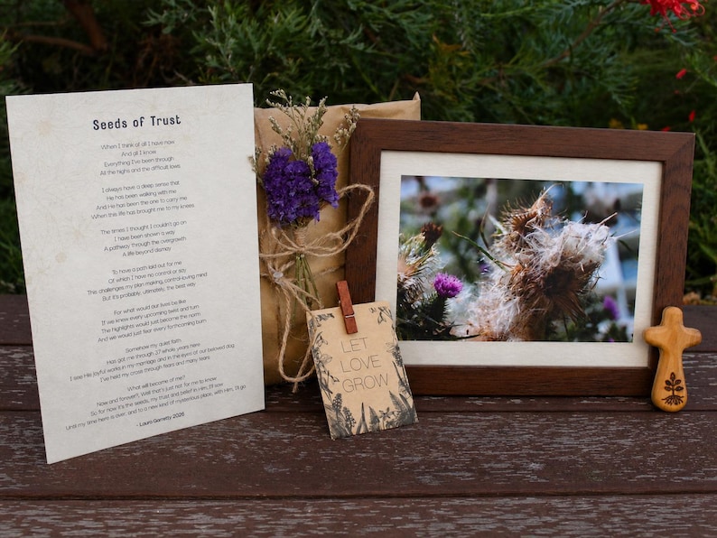 Seeds of Trust flat lay — a framed nature photograph, a hand-burnt olive-wood cross, the printed poem and a Let Love Grow tag